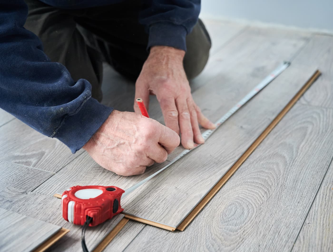 man-hands-drawing-line-on-laminate-timber-plank-2023-04-03-19-24-48-utc Man repairing solid hardwood timber floor