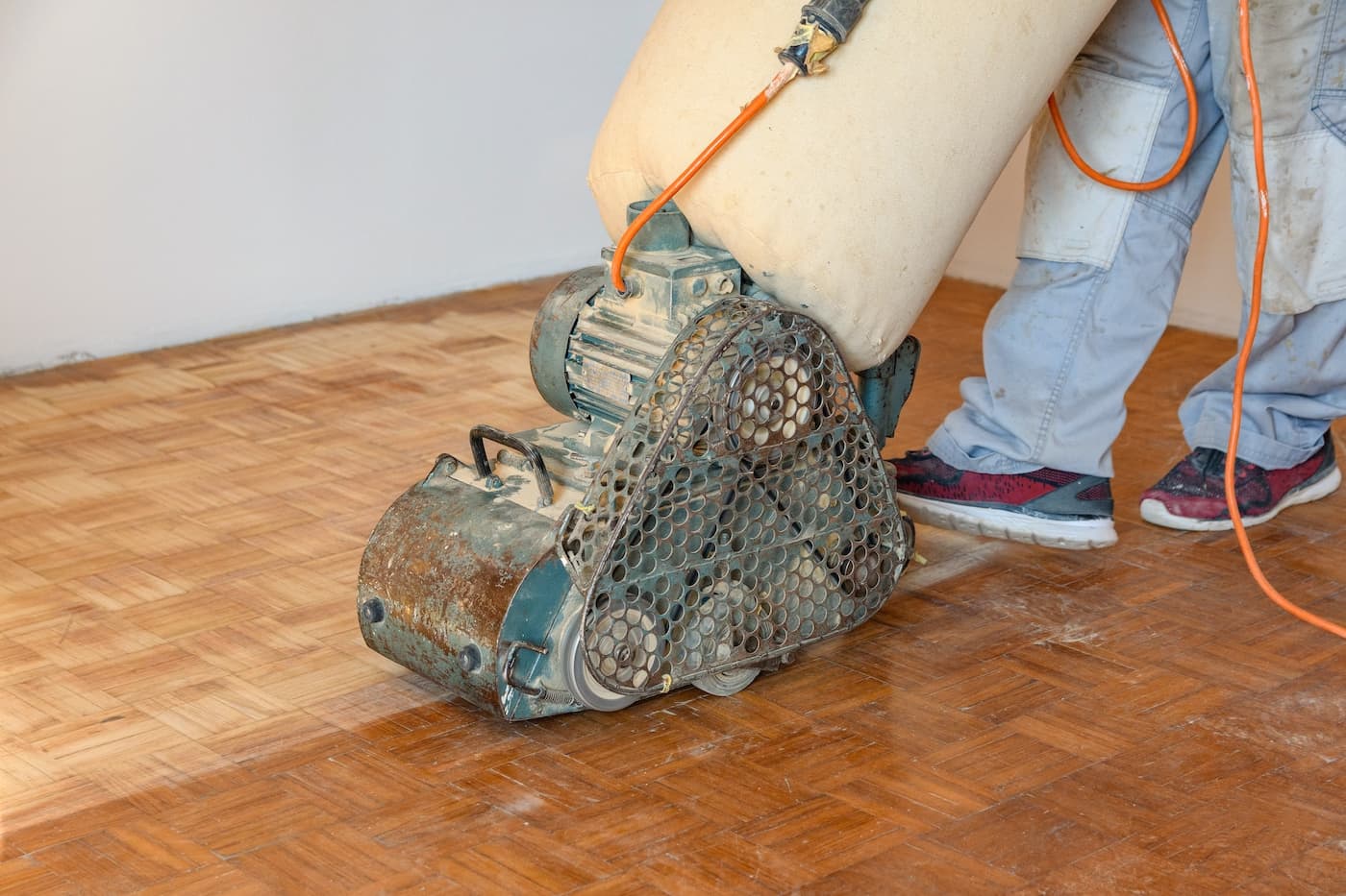 man-sanding-hardwood-floor-with-grinding-machine-2022-11-14-18-03-57-utc sanding a hardwood floor